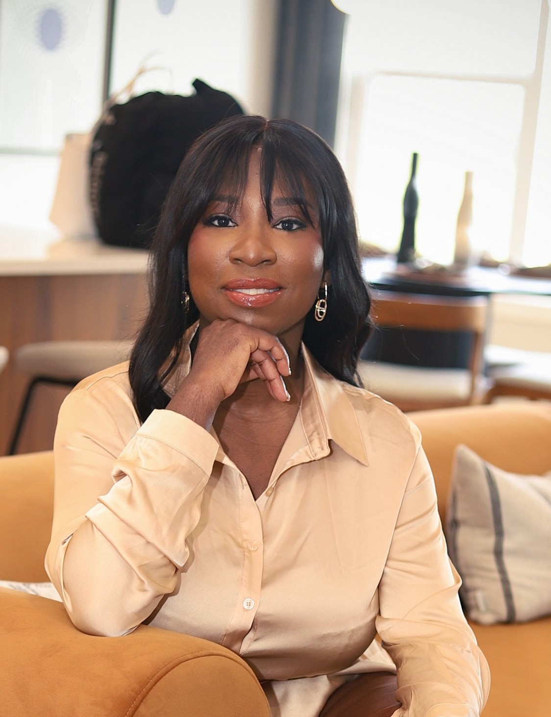 Tolu Amadi seated in a gold satin shirt
